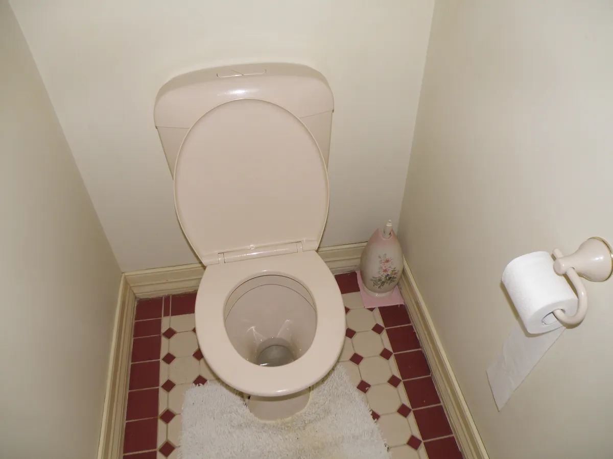 A toilet with the lid up in a small bathroom